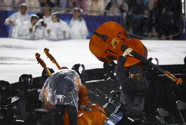 Μουσικοί προσπαθούν να προστατέψουν τα όργανά τους από τη βροχή / Reuters