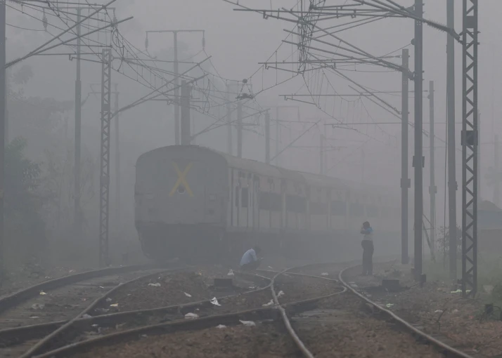 Men wait on a railway track as a train passes by, on a smoggy morning in New Delhi, Anushree Fadnavis/Reuters
