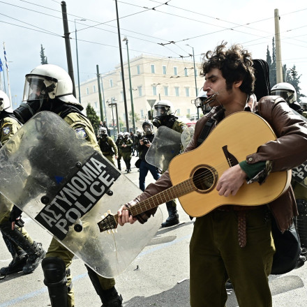 Τέμπη: Η στιγμή που μουσικός παίζει κιθάρα και τραγουδά ενώ δίπλα του πέφτουν μολότοφ και πέτρες