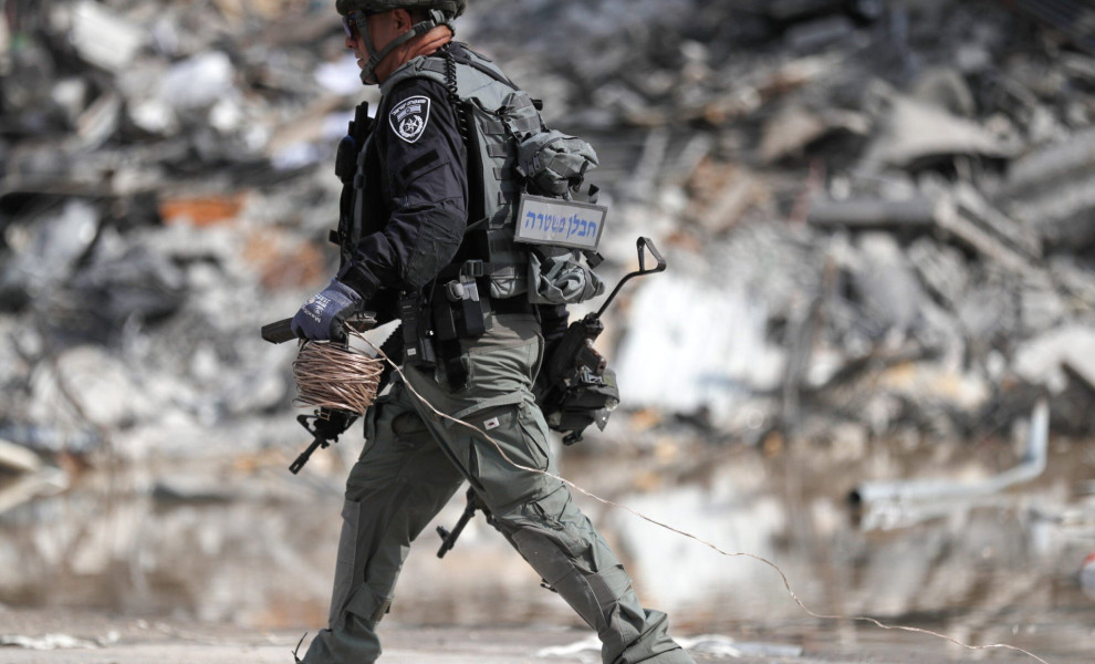 epa10907050 A member of the Israeli security forces carries a weapon used by Hamas fighters at the site of the destroyed police station that was controlled by Hamas militants in the southern city of Sderot, close to the Gaza border, Israel, 08 October 202
